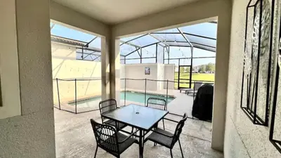 a patio with a table and chairs and a pool at Orlando Villa 6227: The Secret to Your Dream Resort Holiday in Kissimmee