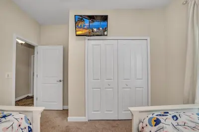 a bedroom with two beds and a tv on the wall at Orlando Villa 6243: The Best Orlando Getaway at Storey Lake in Kissimmee