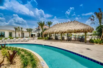 a resort pool with chairs and a thatch roof at Orlando Villa 6243: The Best Orlando Getaway at Storey Lake in Kissimmee