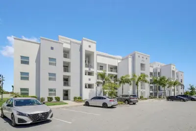 a large white building with cars parked in a parking lot at Orlando Condo 6259: Ultimate Family Retreat on Storey Lake in Kissimmee
