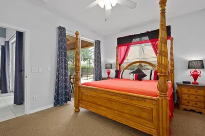 a bedroom with a wooden bed with a red bedspread at Luxury Villa with private Pool Emerald Island Resort Orlando Villa 5074 in Kissimmee