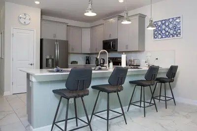 a kitchen with four bar stools at a kitchen counter at The Ultimate Mansion with Private Pool on Storey Lake Resort Orlando Mansion 5287 in Kissimmee