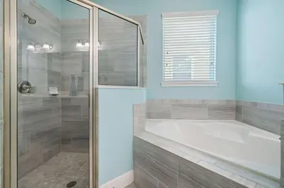 a bathroom with a tub and a glass shower at Indulge in Opulence: Where Comfort Meets Endless Fun in Orlando