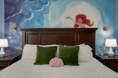 a bedroom with a bed with a mermaid painting on the wall at Outdoor Movie Theatre! Heated Private Pool! 4 Mi to Disney! Grill in Kissimmee