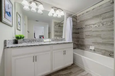 a white bathroom with a tub and a sink and a bath tub at Outdoor Movie Theatre! Heated Private Pool! 4 Mi to Disney! Grill in Kissimmee