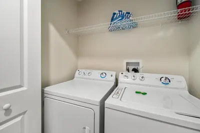 a laundry room with a white washer and dryer at Outdoor Movie Theatre! Heated Private Pool! 4 Mi to Disney! Grill in Kissimmee
