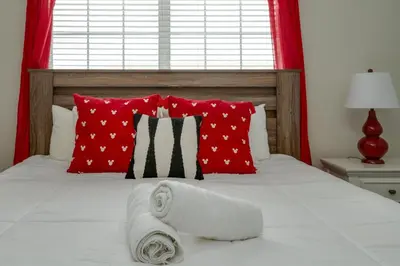 a bed with red pillows and two towels on it at Outdoor Movie Theatre! Heated Private Pool! 4 Mi to Disney! Grill in Kissimmee