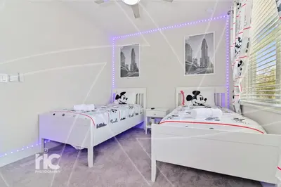 two beds in a white room with purple lights at New Luxury Dream Vacation Home With Gym, 70 inch TV, Private Pool, 4 Bedrooms, 3 Full Baths, High Speed WiFi in Orlando