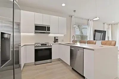 a kitchen with white cabinets and stainless steel appliances at New Luxury Dream Vacation Home With Gym, 70 inch TV, Private Pool, 4 Bedrooms, 3 Full Baths, High Speed WiFi in Orlando
