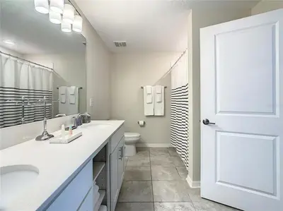 a white bathroom with a toilet and a white door at Beautiful 3bed 2bath Condo close to Disney Parks 344 in Kissimmee