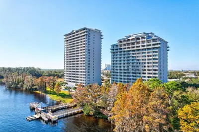 two tall buildings next to a river with trees at LUXURY 1br LAKEVIEW CONDO NEAR DISNEY! in Orlando