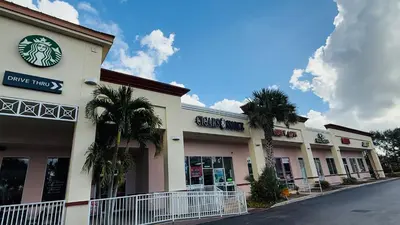 a building with palm trees in front of a street at LUXURY 1br LAKEVIEW CONDO NEAR DISNEY! in Orlando