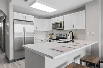a kitchen with white cabinets and a stainless steel refrigerator at LUXURY 1br LAKEVIEW CONDO NEAR DISNEY! in Orlando