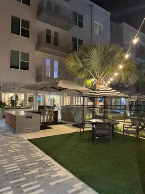a patio with a table and umbrella in front of a building at Modern 1 bedroom Apartment and Den in Orlando in Orlando