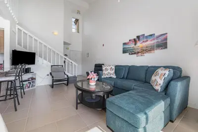 a living room with a blue couch and a table at Family Home w/ Pool & Water Views, Near Disney in Kissimmee