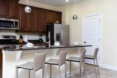 a kitchen with a counter with chairs and a refrigerator at 421 NP - Exquisite Retreat at Encore Resort in Orlando