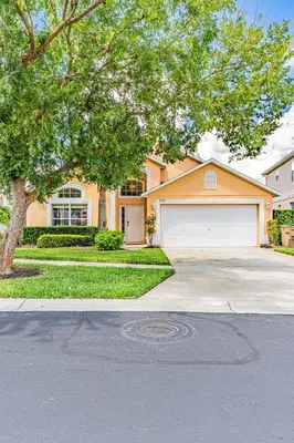 a house with a tree in front of a driveway at Stunning Emerald Island Resort Vacation Home with Pool Spa and Access to Clubhouse in Kissimmee