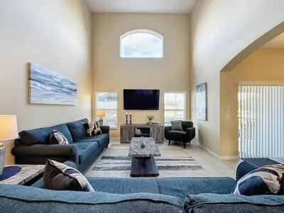 a living room with a blue couch and a tv at Emerald Island Four Bed Pool Home close to Disney villa in Kissimmee