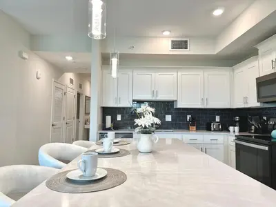 a kitchen with white cabinets and a table with chairs at 2 Bedroom Condo minutes from Disney 325 in Kissimmee