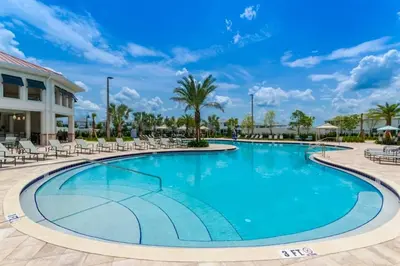 a swimming pool at a resort with chairs and palm trees at 2 Bedroom Condo minutes from Disney 325 in Kissimmee