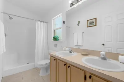 a white bathroom with two sinks and a toilet at Upstay - Games & Private Pool Family Home in Orlando