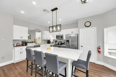 a kitchen with white cabinets and a large island with chairs at Dreamy 6 Bedroom Villa in Orlando6495 in Orlando