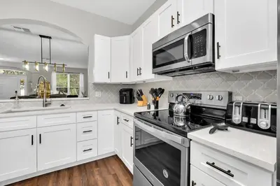 a white kitchen with white cabinets and a microwave at Dreamy 6 Bedroom Villa in Orlando6495 in Orlando