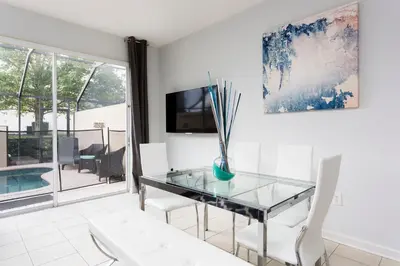 a dining room with a glass table and white chairs at Cozy 3 Bedroom Haven in Orlando6497 in Orlando