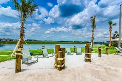 a patio with chairs and palm trees next to a lake at Luxury 2bd 2 bath Condo Home 250 in Kissimmee