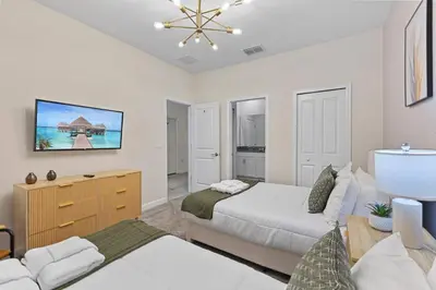 a bedroom with two beds and a tv on the wall at 2869 Epic Themed Mega Home at Storey Lake 7DB in Kissimmee