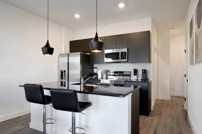 a kitchen with black and white cabinets and black chairs at New great townhouse in The Hub in Kissimmee