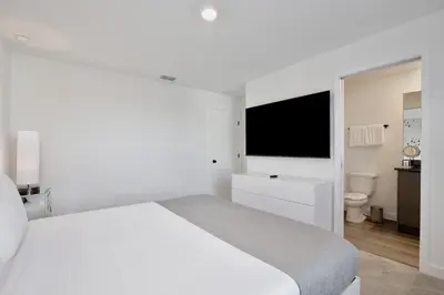 a white bedroom with a white bed and a television at New great townhouse in The Hub in Kissimmee
