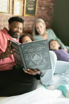 a man reading a book with his family on a bed at Magical Getaway Close to Disney with Heated Pool in Orlando