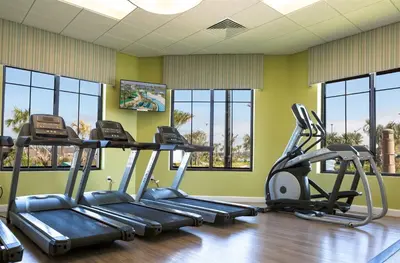 a gym with three tread machines in a room with windows at 4Q/3B Storey Lake Resort, melhor localização! in Kissimmee