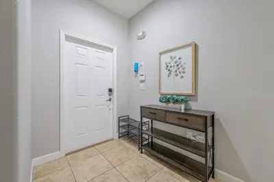 a hallway with a white door and a wooden dresser at PP8962 - 4 Bedrooms w Pool & Resort Access in Kissimmee