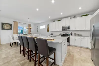 a kitchen with white cabinets and a large island with chairs at The Ultimate Mansion on Solara Resort Orlando Mansion 5304 in Kissimmee