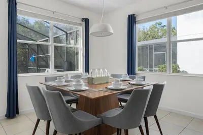 a dining room with a table and chairs and windows at New Listing - Be the First Guest 5 BR - BV468 in Kissimmee