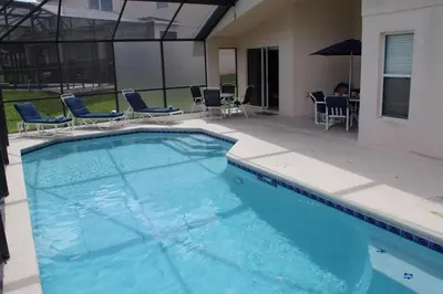 a large swimming pool with chairs and an umbrella at Beautiful 4 Bed In Prime Location in Kissimmee