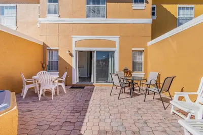 a patio with chairs and a table and a building at Charmosa 3Q/2.5B c/Jacuzzi * Vista Lago * in Kissimmee