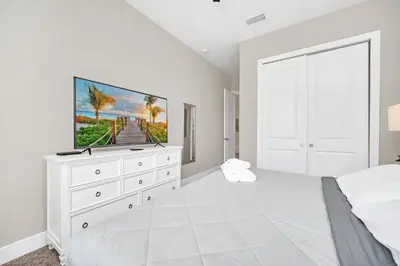 a white bedroom with a tv on a white dresser at NEW amazing unique dream house 5 Min to Disney in Orlando