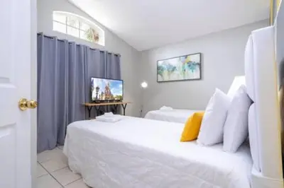 a bedroom with two beds and a television in it at Amazing 5 BR wgame room minutes from Disney in Kissimmee