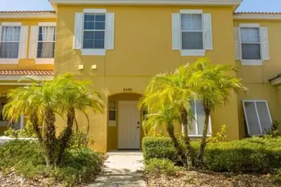 a yellow house with two palm trees in front of it at Cozy 3 BR wprivate pool in Kissimmee