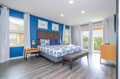 a bedroom with blue walls and a bed with a bench at Cozy 4BR Regal Oaks close to Disney in Orlando