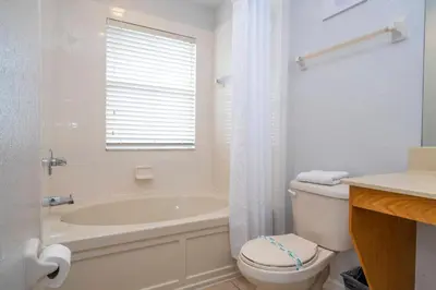 a white bathroom with a tub and a toilet and a sink at Cozy 4BR Regal Oaks close to Disney in Orlando