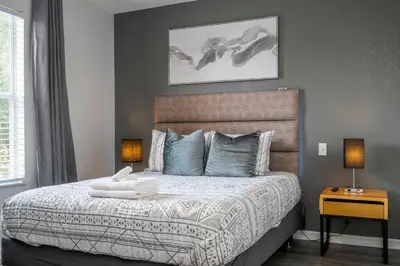 a bedroom with a bed with two lamps and a picture at Cozy 4BR Regal Oaks close to Disney in Orlando