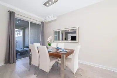 a dining room with a wooden table and white chairs at Gorgeous Storey Lake 4BR in Kissimmee