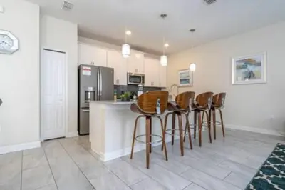 a kitchen with a bar with chairs and a refrigerator at Gorgeous Home with pool and lake view in Kissimmee