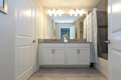 a white bathroom with a sink and a mirror at Gorgeous Home with pool and lake view in Kissimmee