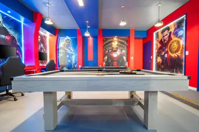 a pool table in a room with superheroes on the walls at Stunning 15 suites close to Disney in Kissimmee