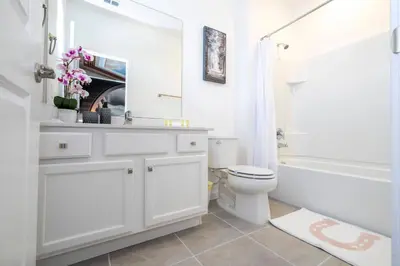 a white bathroom with a toilet and a sink and a tub at Stunning 15 suites close to Disney in Kissimmee